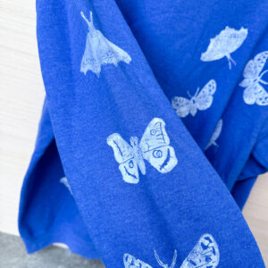 Moths and butterflies printed in white down the bright blue sleeve of a crewneck sweatshirt.