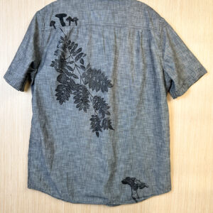 Back of grey short sleeve button down with mushroom and misprinted mountain ash in black ink.