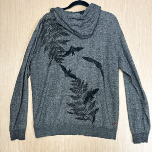 Back of grey hoodie printed with cedar branch growing down from left shoulder and up from right back hem in black ink on a grey hoodie, with black bat prints across the fabric.