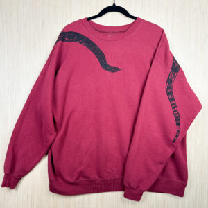 Front of burgundy sweatshirt with black snake head printed coming down from right shoulder, folded over left sleeve showing where tail is printed on back.