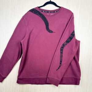 Front of burgundy sweatshirt with black snake head printed coming down from right shoulder, folded over left sleeve showing where tail is printed on back.