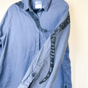 Closeup of sleeve print showing snake tail with front of shirt in background.