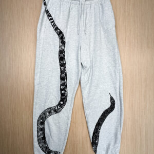 Grey sweats with black snake print with tail at right hip, body looping to bottom edge of right leg, top third and head angled from inseam of left leg, printed up the leg.