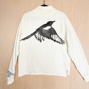 Back of cream colored sweatshirt with life size magpie print in black ink.