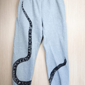 Grey sweats with black snake print with tail at right hip, body looping to bottom edge of right leg, top third and head angled from inseam of left leg, printed up the leg.