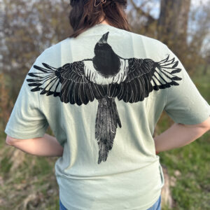 Woman wearing mint green t-shirt with black ink life-size magpie print with wings spread across the back.