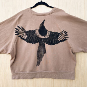 Back of tan hoodie with life-size black-billed magpie with wings spread printed at straight across the back.