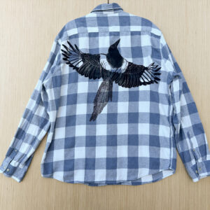 Back of blue and white plaid flannel with life-size black-billed magpie printed at an angle across back panel.