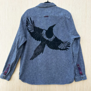 Back of grey button down with black-billed magpie printed with wings spread across the back at an angle, flying to the right.
