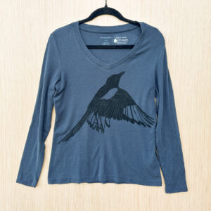 Front of blue v-neck long sleeve t-shirt with life-size flapping magpie printed in black ink across chest.