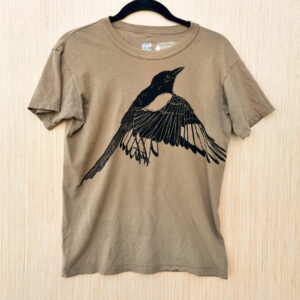Front of green-brown t-shirt with life-size flapping black-billed magpie printed in black ink across the front.