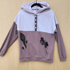 Front of pink color block hoodie with a quarter snap detail down the front and a black ink pika printed popping out of left pocket, beargrass and two indian paintbrush coming out of right pocket.