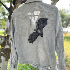 Back of grey shirt with black pallid bat printed across the back from right shoulder to center back.