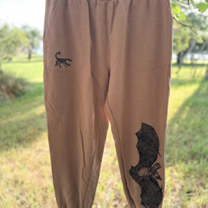 Front of tan joggers with scorpion print in black ink on right pocket, pallid bat printed up on low left leg.